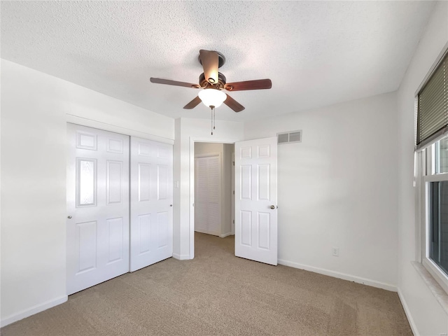 unfurnished bedroom with carpet, a closet, visible vents, a textured ceiling, and baseboards