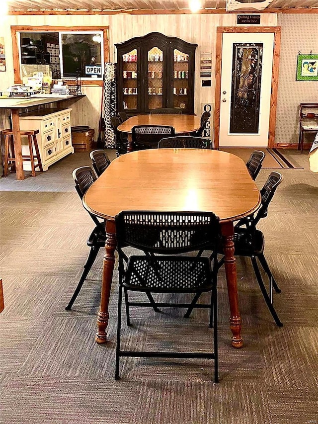 dining area with carpet flooring and wooden walls