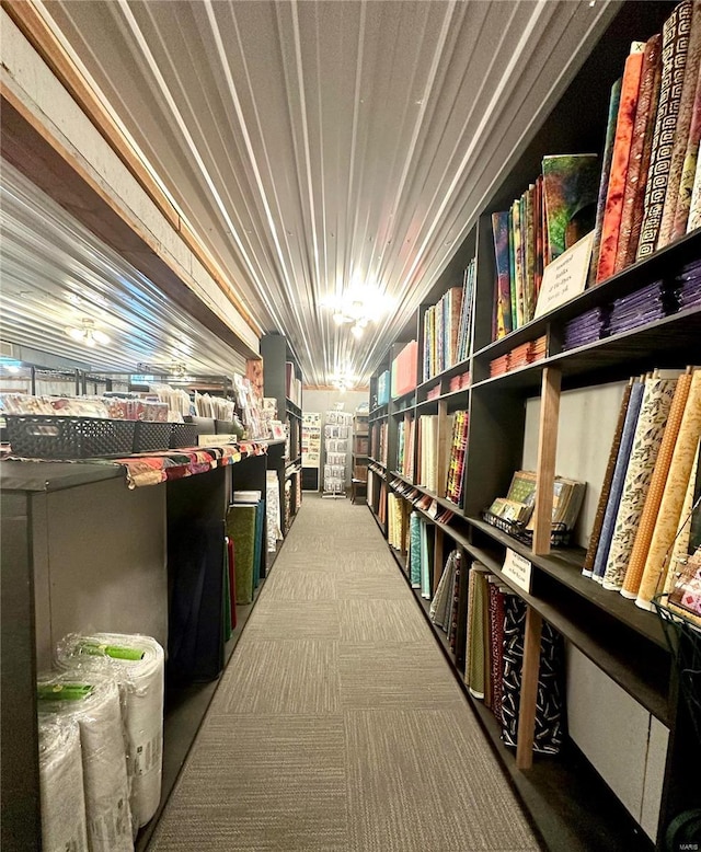 misc room featuring wall of books and carpet flooring