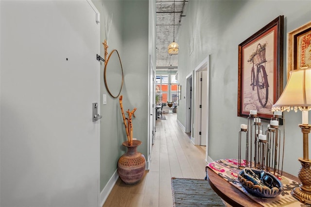 corridor with light wood-style flooring and baseboards