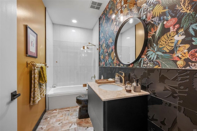 bathroom with bathtub / shower combination, toilet, vanity, visible vents, and wallpapered walls