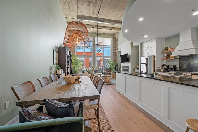 dining area featuring a notable chandelier, a towering ceiling, and light wood finished floors