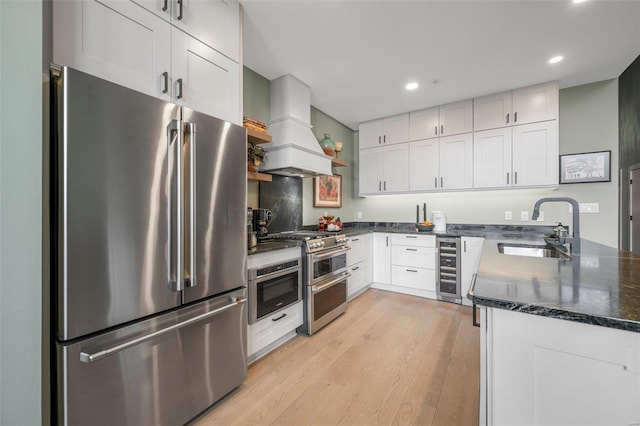 kitchen featuring light wood-style flooring, beverage cooler, a sink, custom exhaust hood, and high end appliances