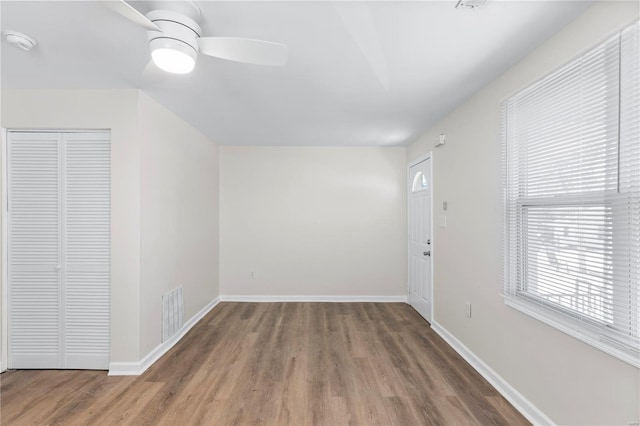 interior space featuring ceiling fan, wood finished floors, visible vents, and baseboards