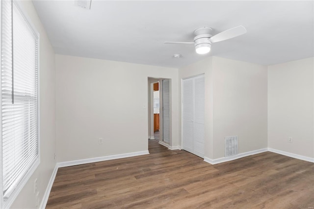 spare room featuring visible vents, ceiling fan, baseboards, and wood finished floors