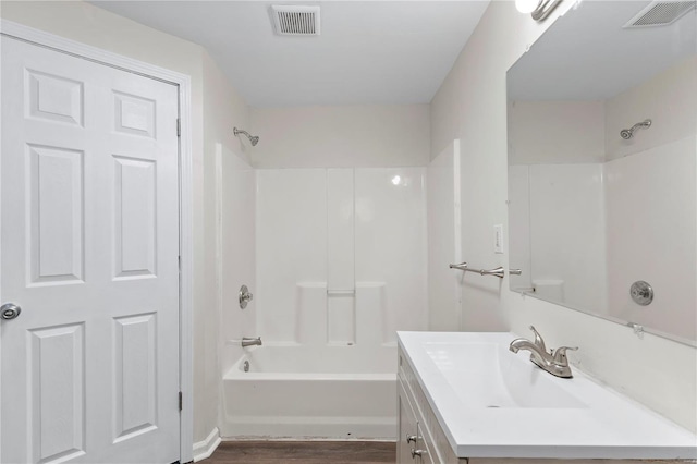 full bathroom featuring washtub / shower combination, visible vents, wood finished floors, and vanity