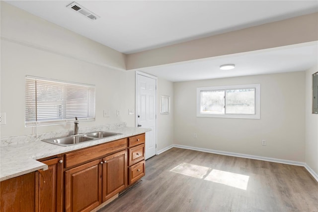 kitchen featuring a sink, visible vents, light countertops, light wood-type flooring, and brown cabinets