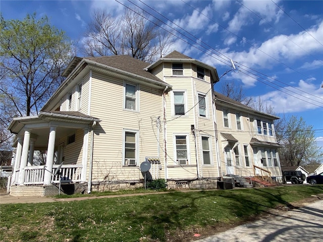 view of front of property featuring a porch, cooling unit, and a front lawn