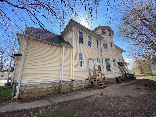 view of home's exterior featuring a shingled roof and entry steps