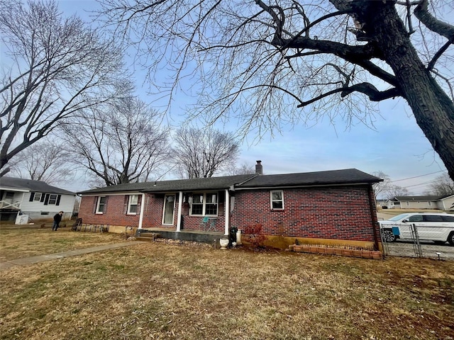 ranch-style home with brick siding, a front lawn, and a chimney