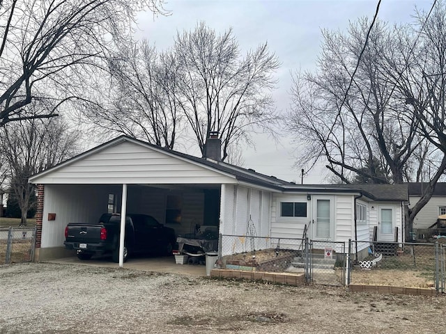 view of front of house with a fenced front yard, driveway, a gate, a carport, and a chimney