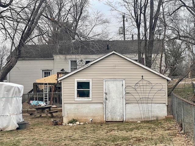 back of property with an outdoor structure and fence