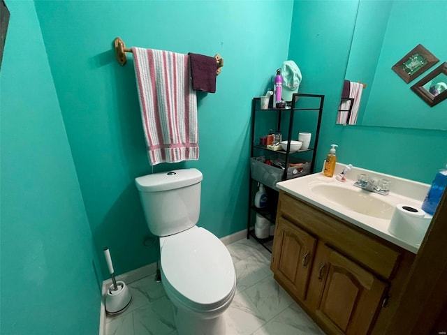 half bath featuring marble finish floor, baseboards, vanity, and toilet