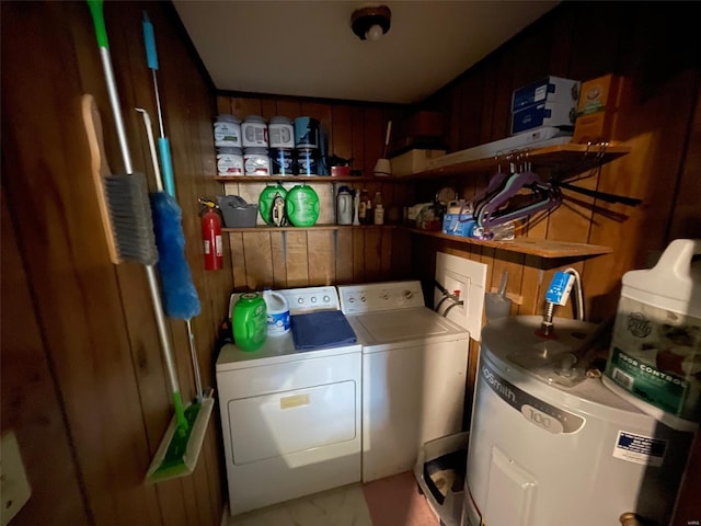 laundry area featuring laundry area, wooden walls, water heater, and independent washer and dryer