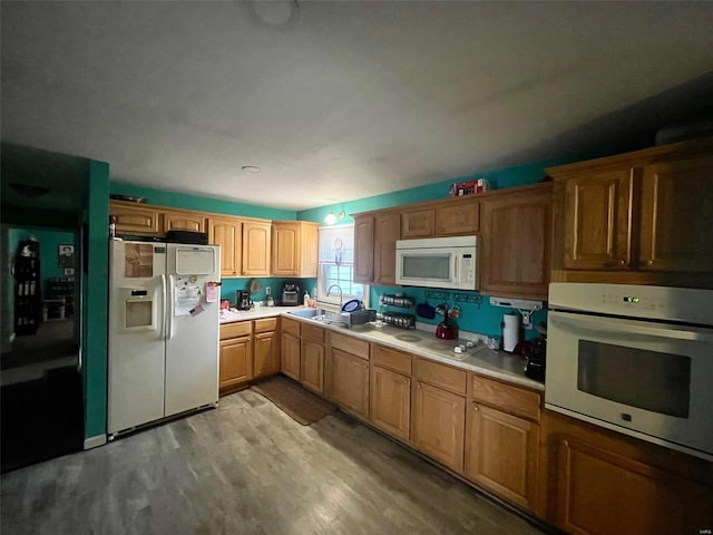 kitchen with light countertops, white appliances, a sink, and light wood-style flooring