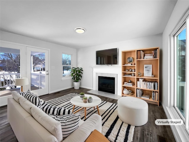 living area featuring dark wood-style floors, visible vents, baseboards, and a premium fireplace