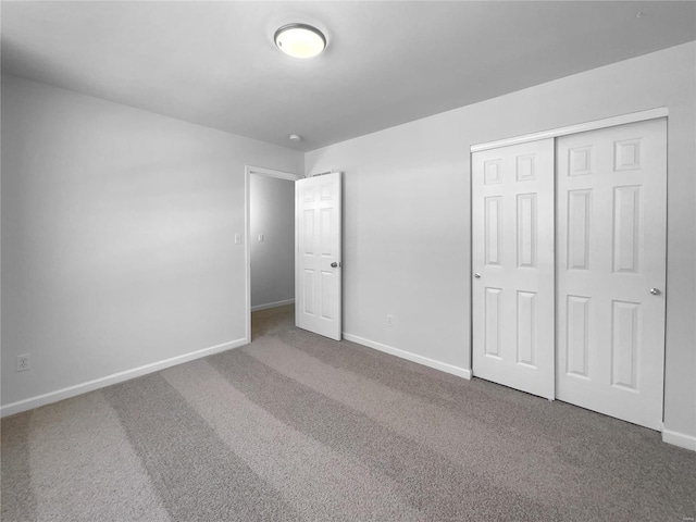 unfurnished bedroom featuring a closet, carpet flooring, and baseboards