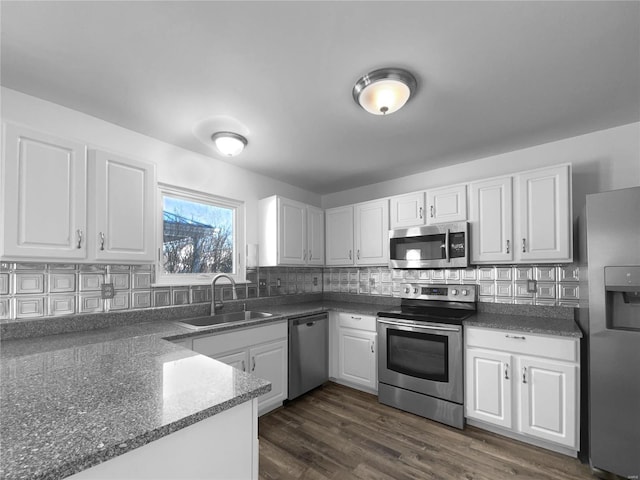 kitchen featuring dark wood-style flooring, stainless steel appliances, decorative backsplash, white cabinets, and a sink