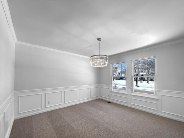 unfurnished room featuring visible vents, a wainscoted wall, ornamental molding, carpet, and a notable chandelier