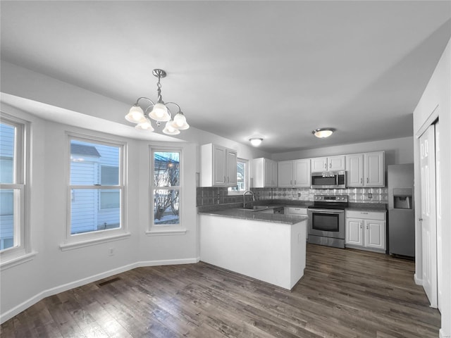 kitchen with dark wood-style floors, stainless steel appliances, visible vents, decorative backsplash, and a sink