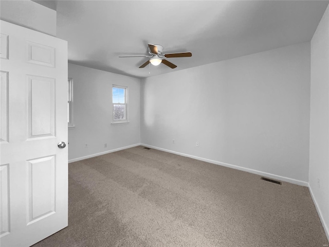 empty room featuring carpet, visible vents, ceiling fan, and baseboards