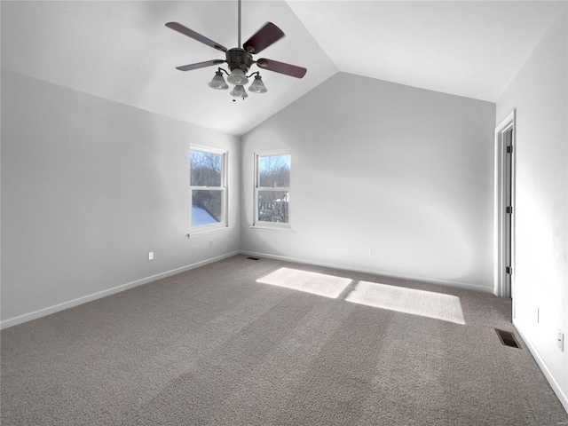 carpeted empty room featuring a ceiling fan, visible vents, vaulted ceiling, and baseboards