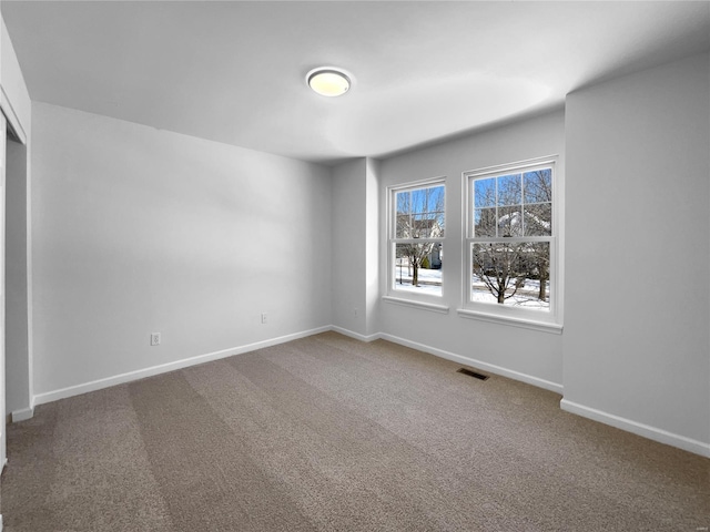 carpeted spare room with visible vents and baseboards