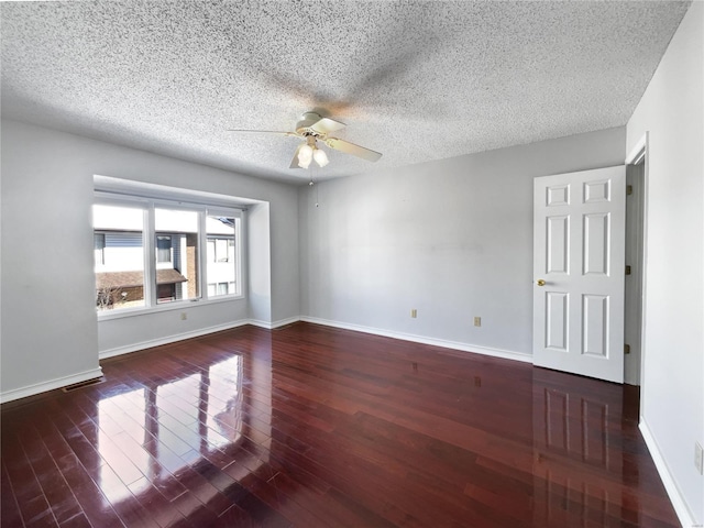 spare room with wood finished floors, visible vents, and baseboards