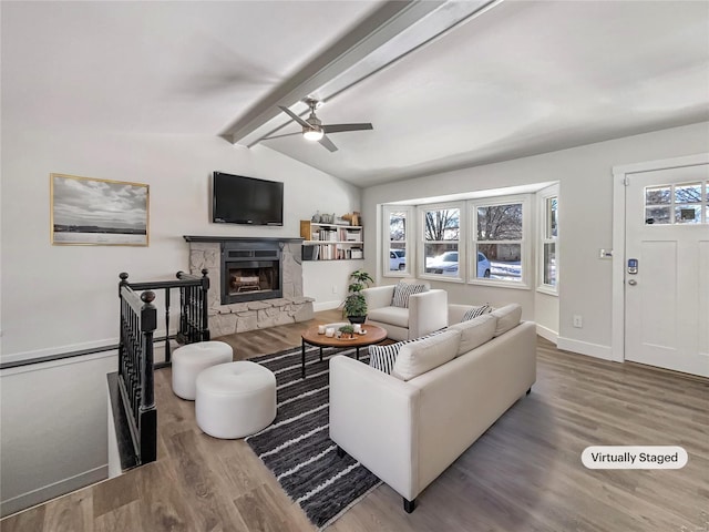 living room featuring vaulted ceiling with beams, a stone fireplace, baseboards, and wood finished floors