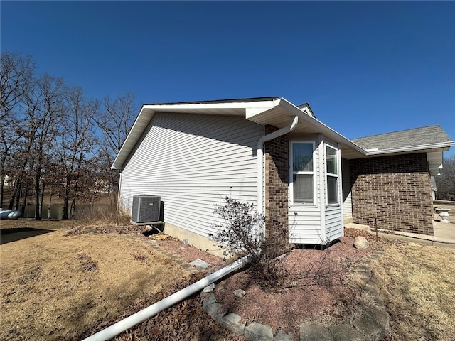 view of side of home featuring central AC and brick siding