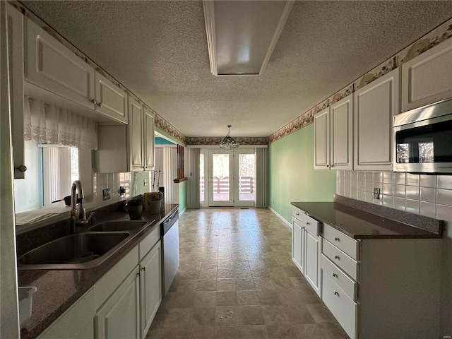 kitchen with dark countertops, decorative backsplash, stainless steel appliances, and a sink