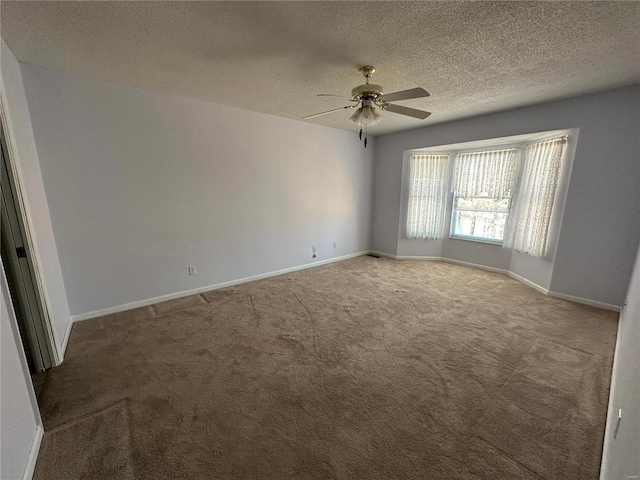 empty room with carpet flooring, ceiling fan, a textured ceiling, and baseboards