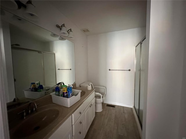 bathroom with a stall shower, visible vents, toilet, and wood finished floors