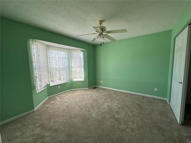 unfurnished bedroom with a textured ceiling, carpet floors, a ceiling fan, and baseboards