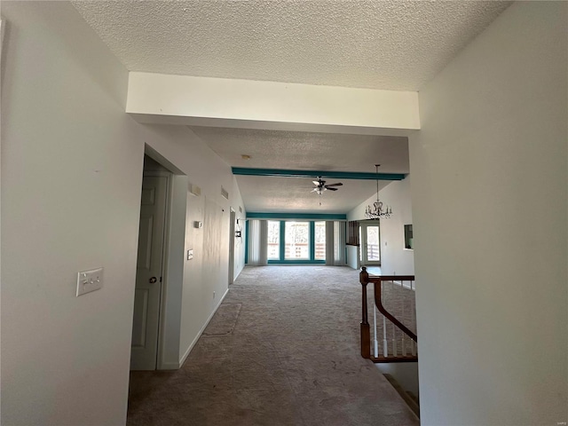 hall with carpet, baseboards, and a textured ceiling