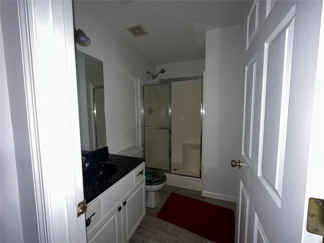 bathroom with toilet, a stall shower, visible vents, and vanity