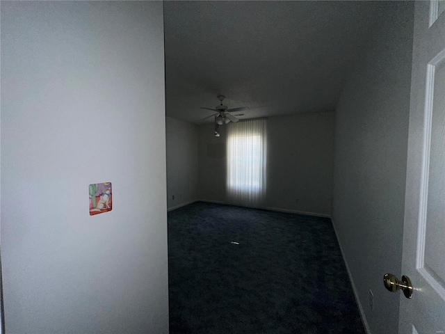 carpeted spare room featuring baseboards and a ceiling fan