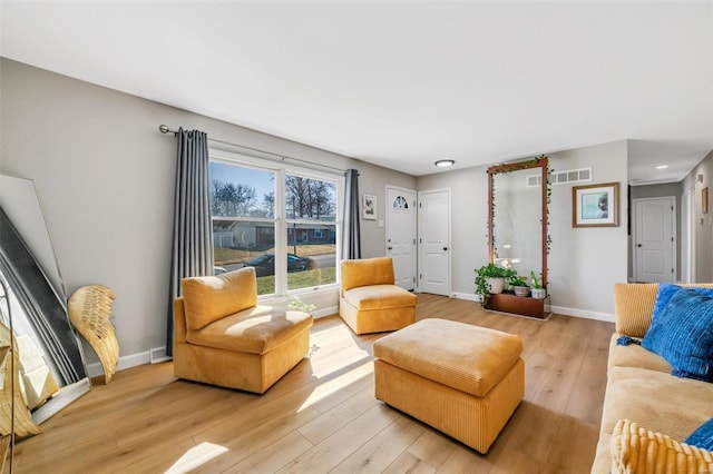 living room with visible vents, light wood-style floors, and baseboards