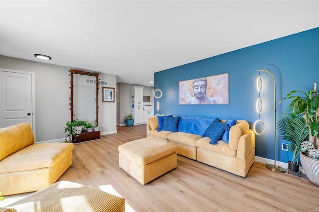 living area featuring visible vents, light wood-style floors, and baseboards