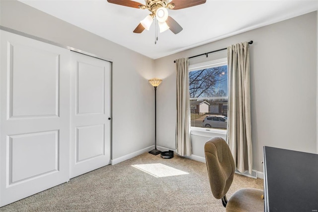 carpeted office space featuring baseboards and a ceiling fan