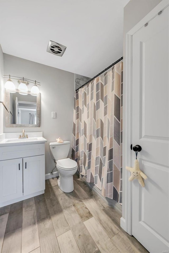 bathroom with visible vents, toilet, a shower with curtain, wood finished floors, and vanity