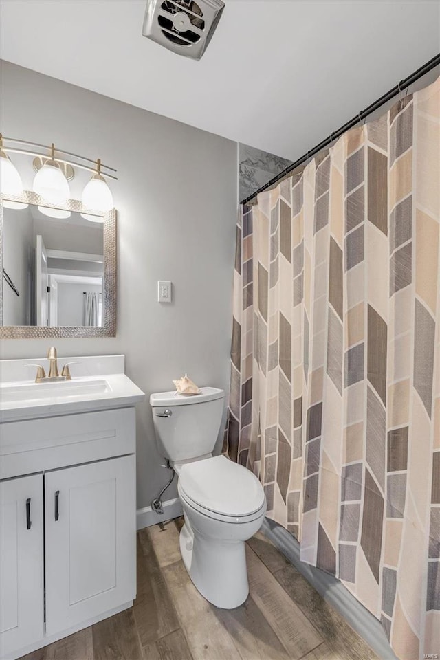 bathroom featuring baseboards, toilet, a shower with curtain, wood finished floors, and vanity