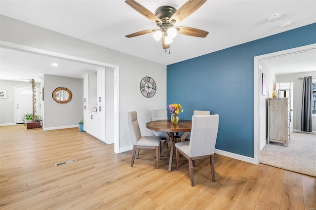 dining area featuring visible vents, a ceiling fan, light wood-style floors, and baseboards