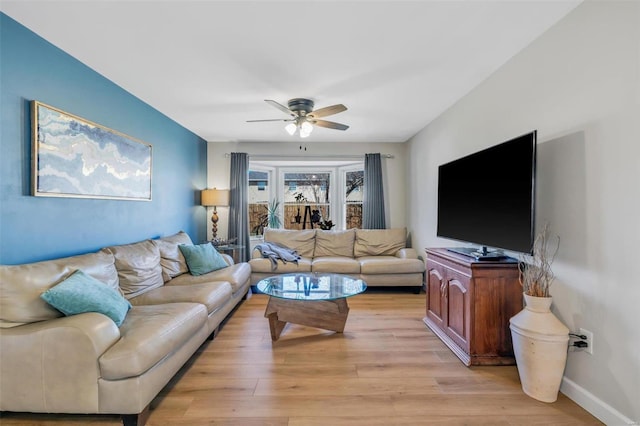 living room featuring baseboards, light wood-style flooring, and a ceiling fan