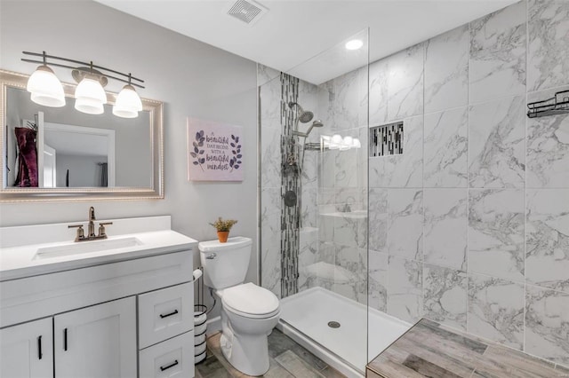 bathroom with vanity, toilet, a walk in shower, and visible vents