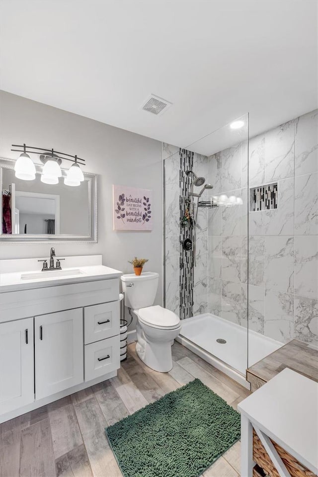 full bath featuring vanity, toilet, a walk in shower, and visible vents