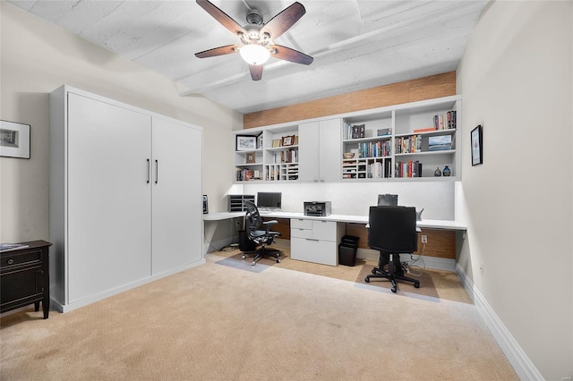 office area featuring light carpet, a ceiling fan, baseboards, built in study area, and beamed ceiling