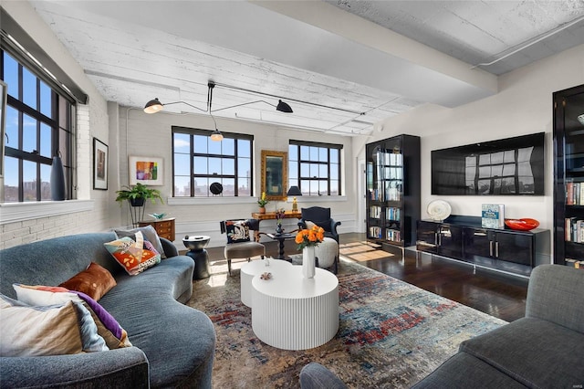 living area featuring brick wall and wood finished floors