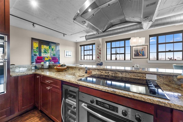 kitchen with black electric stovetop, wine cooler, light stone counters, wall chimney range hood, and dark wood-style floors