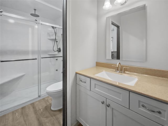 full bathroom with toilet, wood finished floors, a shower stall, and vanity